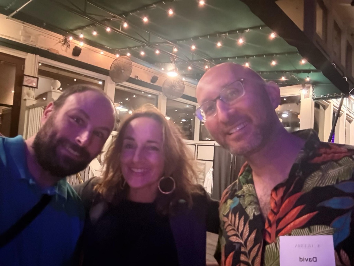 David in a leaf-print shirt, smiling in a selfie beside two other guests under string lights on a patio at night, September 3, 2026